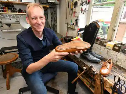 Mit handgefertigtem Ma&szlig;schuh in der Hand: Wilm Denker in der Schusterwerkstatt, in der auch Reitstiefel repariert werden.