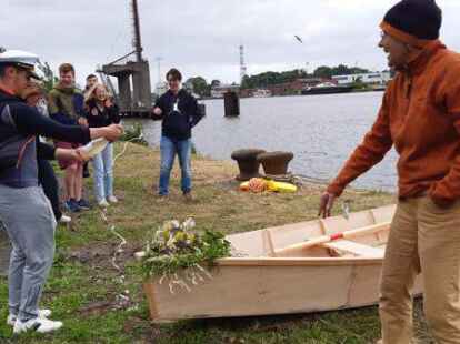 Bootstaufe auf der Teufelsinsel: Hier verpasst &bdquo;Team-Kapit&auml;n&ldquo; Ahmed El Abed dem Ruderboot &bdquo;Zyzz&ldquo; zur Taufe eine Sektdusche, rechts: Anleiterin Inka Petersen vom Arbeitskreis f&uuml;r historischen Schiffbau in Ostfriesland.