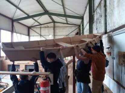 Mit vereinten Kr&auml;ften: Vor dem Stapellauf mussten die beiden Ruderboote vom Typ Bevin&rsquo;s Skiff erst einmal aus der oberen Werkstatt der Vereinswerft nach unten bugsiert werden. BILD: Gaby Wolf