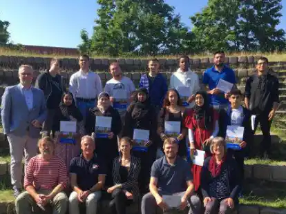 Das Bild zeigt die Absolventen der Sprachf&ouml;rderklasse mit BBS II-Schulleiter Bj&ouml;rn Holzgrabe (links) und weiteren Lehrkr&auml;ften und Schulsozialp&auml;dagogen.