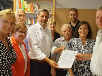 SPD-Ortsvorsitzender Heiner Bilger (rechts) &uuml;bergab Bauminister Olaf Lies (wei&szlig;es Hemd, Mitte) eine Mappe mit den bisherigen Ergebnissen des St&auml;dtebauf&ouml;rderprogramms &bdquo;Sozialer Zusammenhalt&ldquo; in Ahlhorn. Dar&uuml;ber sprachen am Mittwoch unter anderem die SPD-Mitglieder (von links) Susanne Mittag, Renate Geuter,  Thorsten Schmidtke, Kerstin Johannes, Hartmut Giese, Thore G&uuml;ldner, Pia van de Lageweg.