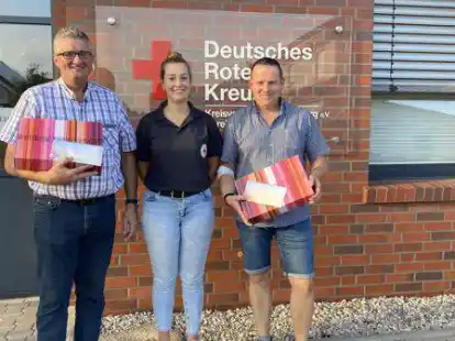 Laura V&ouml;lkerding, Vorsitzende der DRK-Ortsgruppe Molbergen (Mitte) &uuml;berreicht ein Weinpr&auml;sent und einen Essensgutschein an Albert Schlangen (links) und Jens Meyer f&uuml;r deren 100. Blutspende.