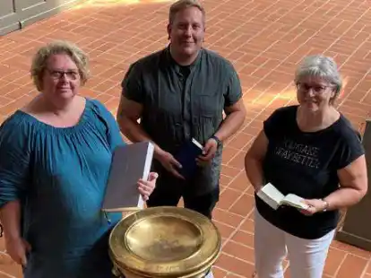 Pfarrerin Uta Brahms (links) sowie Keven Eggers und Linda Bahr vom Hospizkreis Ganderkesee-Hude laden  zum Hospiz-Gottesdienst ein. Am Taufbecken haben sie sich versammelt, weil die Taufe laut Pastorin Brahms f&uuml;r die Auferstehung steht.