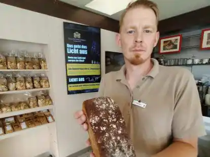 Verk&auml;uferTobias Kresse in der Gr&uuml;nhoff Filiale Parkstra&szlig;e in Norden mit dem Aktionsplakat im Hintergrund.