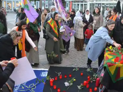 Kundgebung gegen die Gewalt gegen Frauen auf dem Auricher Marktplatz. Die Teilnehmer legen Blumen vor den Fotos get&ouml;teter Frauen nieder.