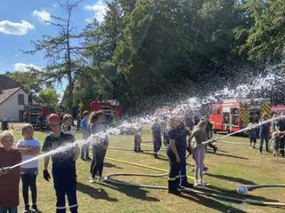 Erste L&ouml;schversuche: Mitglieder der Jugendfeuerwehr Wiefelstede zeigten interessierten Kindern in Dringenburg, wie beim L&ouml;schen eines Brandes vorgegangen wird.