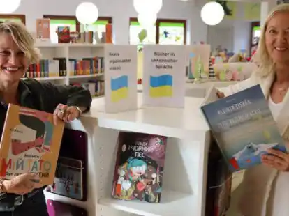 B&uuml;chereileiterin Birgit Meyer-Beylage und die Leiterin des Katholischen Bildungswerks Nicola Fuhler am Regalw&uuml;rfel voller Kinderb&uuml;cher auf Ukrainisch oder auf Deutsch und Ukrainisch.