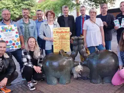 Auf dem Festplatz &bdquo;Unner de Boomen&ldquo; (von links): Marvin Liebtrau (Alte Post), Oliver van Grieken (Gemeinwesenarbeiter), Ronald B&uuml;rger (Pier 29), Jenne Hempel (Das Boot), Sven Ocken (Grundschule Cirksena), Elfriede Meyer (B&uuml;rgerverein), Holger Veddeler (Schweizer Kirche), Heiner Dorkowski (Johannes-Gemeinde), Carola Clemens mit &bdquo;Lotta&ldquo; (Sp&ouml;ldeel Transvaal), Rainer Hempel (Das Boot), Annica Wollny (FC Frisia) und Andrea Haak (Quartiersmanagerin). Elfriede Meyer zeigt das Plakat des Stadtteilfestes von 1982.