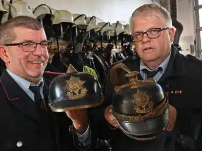 Von der Lederhaube zum Helm: Ortsbrandmeister Ralf Ackmann (r.) und Stellvertreter Michael Engelbarts-Bremer zeigen im Feuerwehrhaus Relikte aus Hintes Feuerwehrgeschichte.