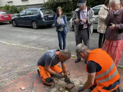 Die BEE-Mitarbeiter Karl-Heinz Giesen und Horst Davids verlegen die beiden neuen Steine, Cosima Artmann (links) von der BBS II verlas im Anschluss die Biografien. Rechts Alan und Barbara Price, die Tochter von Heinz van der Walde.