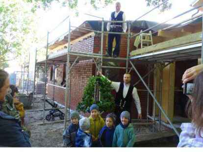Die Zimmerleute Ulf Wiechmann (unten)  und Heiko Posegga (auf dem Ger&uuml;st) h&auml;ngten den Richtkranz auf.