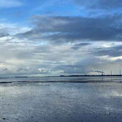 Blaue Stunde im Wattenmeer: Blick von Horumersiel auf Wilhelmshaven mit Umschlagbr&uuml;cke, Hafen, Kohlekraftwerk.
