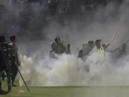 Polizisten und Soldaten stehen inmitten von Tr&auml;nengasrauch bei einem Erstliga-Spiel zwischen Arema FC und Persebaya FC. Bei schweren Ausschreitungen im Anschluss an ein Fu&szlig;ball-Spiel in der indonesischen Provinz Ost-Java sind mindestens 174 Menschen ums Leben gekommen.
