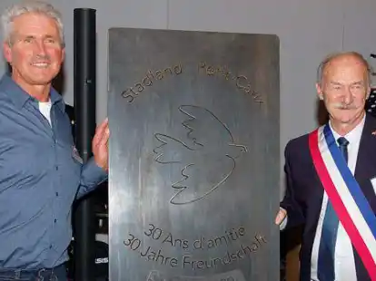 Die beiden B&uuml;rgermeister Hans Schwedt (links) und Patrice Phillipe enth&uuml;llten das Gastgeschenk der Gemeinde Petit-Caux, eine zwei Meter hohe Stahlplatte, in der die Inschrift &bdquo;Stadland Petit-Caux, 30 Ans d&rsquo;amiti&eacute;, 30 Jahre Freundschaft, 1990 bis 2020&ldquo; und eine Friedenstaube eingestanzt sind.
