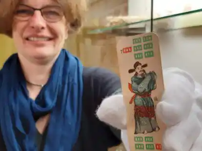 Die stellvertretende Direktorin der Naturforschenden Gesellschaft zu Emden von 1814, Caroline Schott, mit einer Karte aus einem Mahjong-Spiel, das beim Keller-Umr&auml;umen im Corona-Lockdown gefunden wurde und jetzt Teil der Ausstellung &bdquo;Souvenirs aus China?&ldquo; ist.