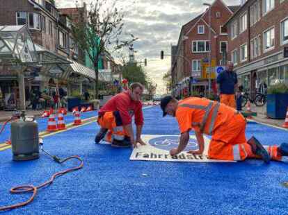 Knallblau ist nicht nur die Neutorstra&szlig;e, sondern sind auch die Schuhsohlen von Alexander-Willem Altergott, der am Mittwochmittag gemeinsam mit Andreas Altergott den Schriftzug Fahrradstra&szlig;e anbrachte. Kollege Steffen Schleenstein sah im Hintergrund zu.