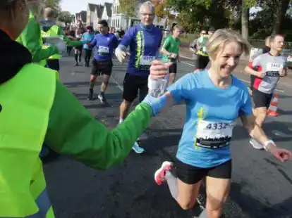 Freude am Laufen: Gunna Arends nimmt beim Halbmarathon Wasser von einer Helferin entgegen. Nils Petersohn m&ouml;chte auch einen haben. Beide kamen nach etwa 1:55 Stunden ins Ziel.