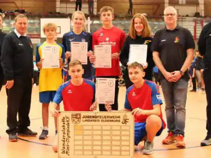 Nach der Siegerehrung zur Mini-Olympiade: Vorne kniend der Gesamtsieger Jugendfeuerwehr (JF) Schierbrok-Sch&ouml;nemoor mit der Wanderplakette. Mit dabei (hinten, von links): Yvonne Meyer (stellvertretende Fachbereichsleiterin Wettbewerbe), Kreisjugendfeuerwehrwart Werner Mietzon, JF Beckeln (Platz 2), JF Prinzh&ouml;fte (Platz 3), JF Hude (Platz 4) JF Colnrade (Platz 5), Andr&eacute; Gerke (stellvertretender Kreisjugendfeuerwehrwart) und Sascha Meister (Fachbereichleiter Wettbewerbe).