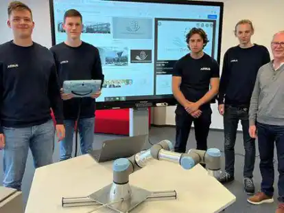 Die Maschinenbau-Studenten Jannik Brauer, Noah L&uuml;demann, Justin Albeck und Tristan Reim (von links) unterst&uuml;tzen Gesch&auml;ftsf&uuml;hrer Dieter Sichau bei der Einrichtung des digitalen Lernorts. Im Vordergrund ist der neu angeschaffte Roboter zu sehen.