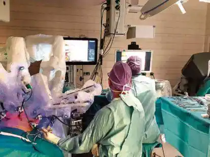 Blick in den OP: &Uuml;ber der Patientin sieht man die Roboter-Arme. Ganz rechts sitzt Chefarzt Dr. Muneer Deeb und steuert das Ger&auml;t.