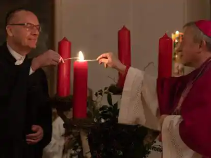 Bischof Thomas Adomeit (links) und Weihbischof Wilfried Theising entz&uuml;nden gemeinsam den Adventskranz.