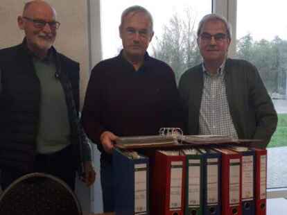 Sechs dicke Ordner voll mit der Vereinschronik und noch zwei mit Bildern zum Kunstrasenplatzbau: TuS-Gesch&auml;ftsf&uuml;hrer Helmut Kohle und die beiden Chronik-Erfasser Johann Alberts und Dieter Harberts.