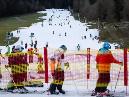 Wintersportler stehen am Streidhang im Skigebiet Brauneck an einem Lift an. Viele Skigebiete in Bayern leiden aktuell unter Schneemangel.