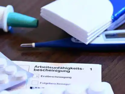 Ein Fieberthermometer, Medikamente und eine &auml;rztliche Arbeitsunf&auml;higkeitsbescheinigung (Krankmeldung) liegen auf einem Nachttisch (gestellte Szene). Mit der kalten Jahreszeit nehmen auch die Infektionen mit Influenza wieder zu. Dies ist auch in Ostfriesland deutlich sp&uuml;rbar. (Symbolbild)