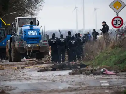 Schwere R&auml;umfahrzeuge entfernen im Beisein der Polizei die von Klimaaktivisten errichteten Barrikaden.