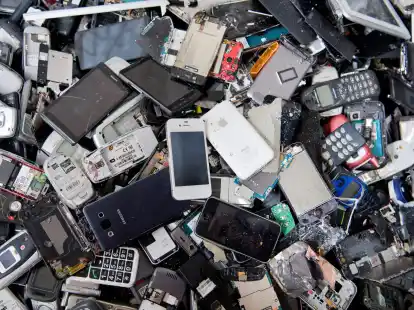 Alte Handys und Smartphones liegen in einem Container, ehe sie geschreddert werden.