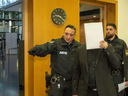 Im Strafjustizzentrum bringen zwei Justizwachtmeister einen Mann in den Sitzungssaal. Er ist zusammen mit seinem Sohn am Amtsgericht Augsburg angeklagt.