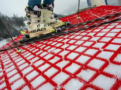 Ein Mann steht mit seinen Skiern auf einer Skipiste, die mit speziellen Kunststoff-Matten pr&auml;pariert wurde. Die Matten k&ouml;nnen das ganze Jahr &uuml;ber zum Skifahren verwendet werden.