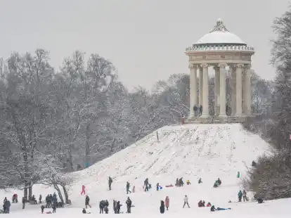 Kinder und Erwachsene rodeln am H&uuml;gel des Monopteros im Englischen Garten in M&uuml;nchen.