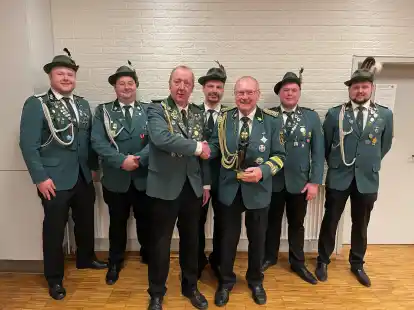 Hans Raker erh&auml;lt die Ehrung zum Sch&uuml;tzen des Jahres. Hier gratuliert der Sieger des Vorjahres, Klaus Bohmann. Im Hintergrund die Verantwortlichen der f&uuml;nf Z&uuml;ge.