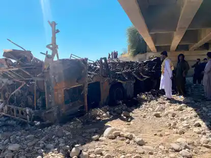 Menschen betrachten das verbrannte Wrack eines verungl&uuml;ckten Busses, der mit rund 50 Menschen an Bord in eine Schlucht gest&uuml;rzt ist.