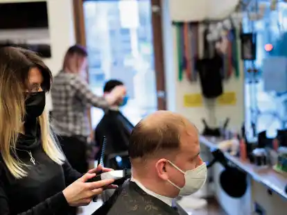 Andrea Siepert-Fichter (l) frisiert Benjamin Hartwig in ihrem Salon in Berlin.