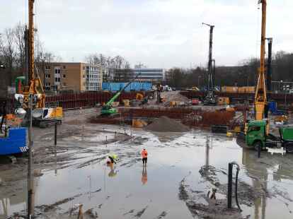 Die drei gro&szlig;en Baumaschinen ragen aus der Baugrube f&uuml;r den Neubau des Klinikums heraus; hinten ist bei den blauen Containern die vierte, kleinere Maschine f&uuml;r Mikropf&auml;hle zu sehen.