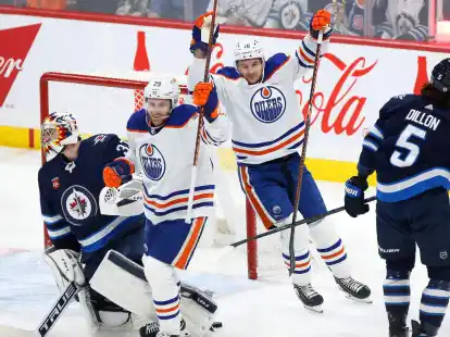 Zach Hyman (18) und Leon Draisaitl (29) von den Edmonton Oilers feiern Draisaitls Tor gegen Connor Hellebuyck (l), Torwart der Winnipeg Jets.