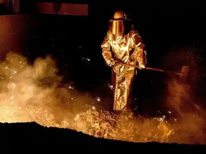 Ein Mitarbeiter schaufelt im Stahlwerk der Salzgitter AG Sand in eine Abstichrinne am Hochofen.