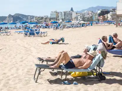 Menschen sonnen sich am Strand von Poniente in Spanien.