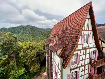 Hinter einem Fachwerkhaus in Colmar Tropicale ist der Dschungel der Berjaya Hills zu sehen.