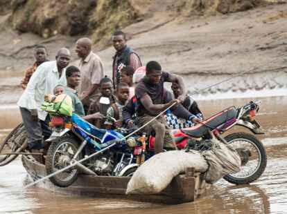 Nach dem Zyklon transportieren M&auml;nner in Malawi ihre geretteten Habseligkeiten mit einem Holzboot.