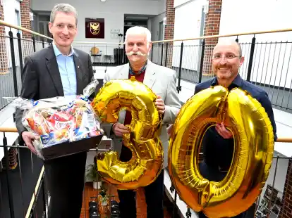 B&uuml;rgermeister Ralf Wessel (von links) &uuml;berreichte J&uuml;rgen L&uuml;dtke einen Pr&auml;sentkorb mit &bdquo;Nervennahrung&ldquo; f&uuml;r die n&auml;chste Sitzung des Seniorenbeirats, Fachdienstleiter Christian Hallanzy gratulierte ebenso zum 30-j&auml;hrigen Bestehen.