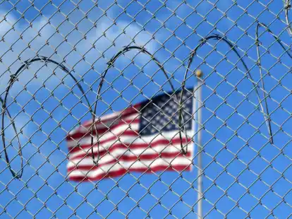 Eine US-Flagge hinter Zaun und Stacheldraht auf dem Marinest&uuml;tzpunkt Guant&aacute;namo Bay auf Kuba. Hier betreiben die USA seit mehr als 21 Jahren ein umstrittenes Gefangenenlager.