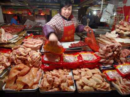 Eine Verk&auml;uferin auf einem Markt in China legt Gefl&uuml;gel aus.