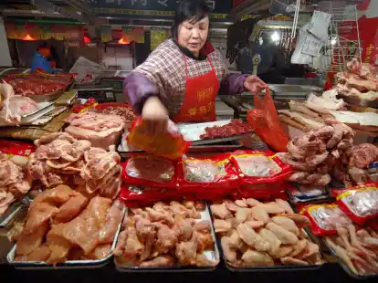 Eine Verk&auml;uferin auf einem Markt in China legt Gefl&uuml;gel aus.
