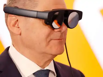 Bundeskanzler Olaf Scholz mit eier AR-Datenbrille (Augmented Reality) zur Prozess&uuml;berwachung einer Maschine.