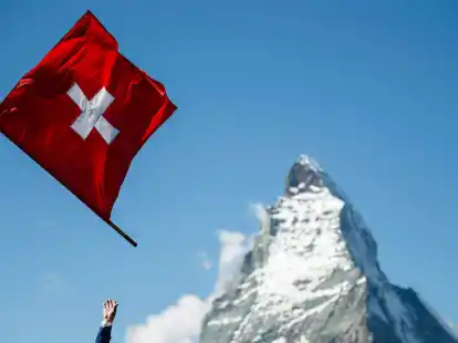 Ein Fahnenwerfer mit der Schweizer Flagge in Aktion vor der Kulisse des Matterhorns.
