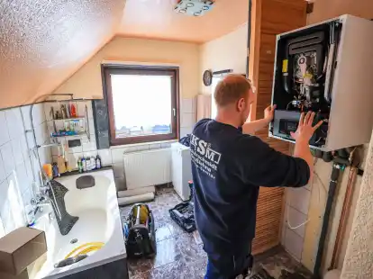 Ein Mitarbeiter einer Sanit&auml;r- und Heizungsbaufirma installiert eine moderne Gasbrennwerttherme in einem Einfamilienhaus.