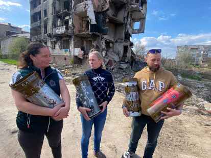 Anke Heller (links) und Renate Brunken (Mitte) mit dem ukrainischen Freiwilligen Vlad Pugach. Sie halten von K&uuml;nstlern bemalte &Uuml;berreste von Geschossen in der Hand, die auf einer Auktion verkauft werden sollen.